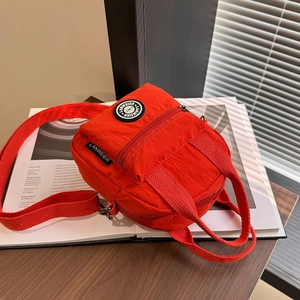 Red nylon multi-functional handbag with adjustable shoulder strap and round logo