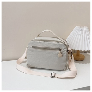 Close-up of lightweight nylon crossbody bag with textured fabric and zipper pocket