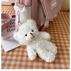 Detail of cute white plush bear pendant hanging on a pink canvas bag with FASHION label