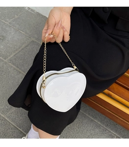 Detailansicht der weißen herzförmigen Tasche mit goldener Kette und Reißverschluss