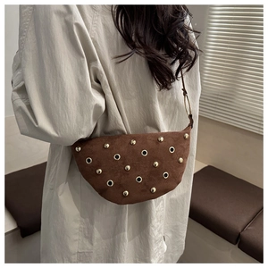 Détails d'un sac hobo en daim marron avec rivets dorés et anneaux métalliques