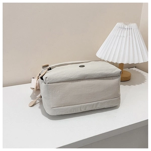 Detail view of the beige nylon shoulder bag with zip closure and woven strap