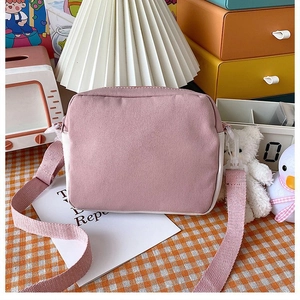 Detailed view of pink and white canvas crossbody bag on a checkered background
