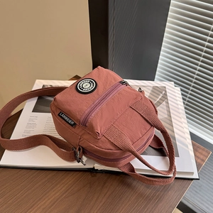 Pink waterproof nylon crossbody bag with dual zipper layers and adjustable strap