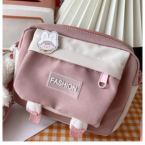 Close-up of a pink and white canvas crossbody bag with a cute rabbit and fashion tag