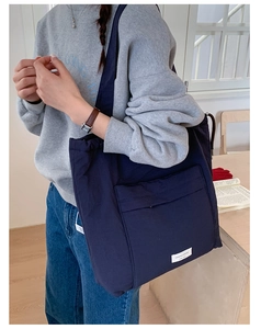 Detail view of a navy blue canvas tote bag featuring a large front pocket and woven label