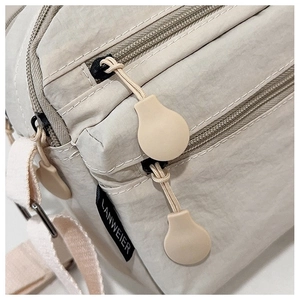 Detail view of water-resistant nylon shoulder bag with zipper and brand label tag