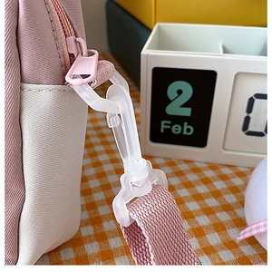 Detail of pink and beige canvas bag showing side zipper, strap and white plastic hook
