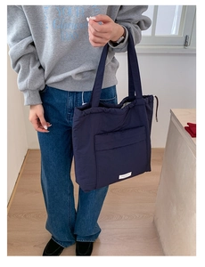 Detailed close-up of navy blue quilted tote bag with white label and drawstring