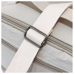 Close-up of adjustable strap with metal buckle and double zippers on a nylon tote bag
