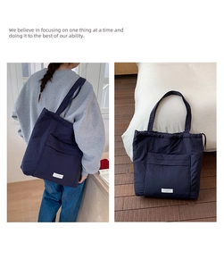 Detail of navy blue nylon tote bag with drawstring closure and large front pocket