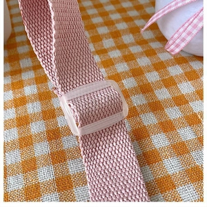 Macro shot of pink canvas shoulder strap featuring a clear plastic adjustment buckle
