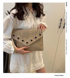 Pochette enveloppe beige chic avec rivets argentés portée par un mannequin en dentelle