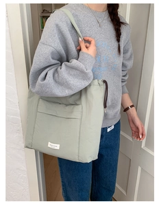Detail of light green nylon tote bag featuring front pocket and brown drawstring closure