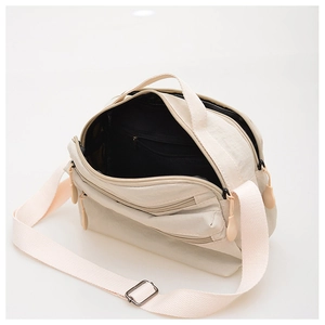 Detail view of cream nylon crossbody bag showing multiple zipper pockets and adjustable strap