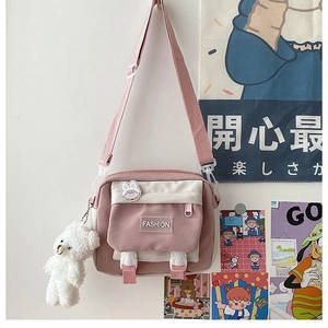 Detail view of pink and white canvas crossbody bag with cute plush bear charm