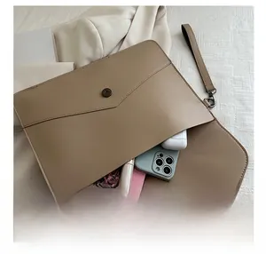 Détail montrant la capacité interne de la pochette enveloppe en cuir kaki avec rivets