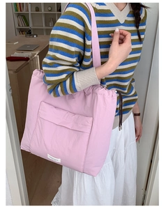 Detailed view of pink nylon tote bag featuring drawstring closure and white brand label