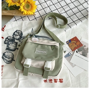Detail view of small canvas crossbody bag with green contrast flap and buckle closures