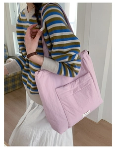 Detail of a large pink padded tote bag showing side-back view and soft nylon fabric texture
