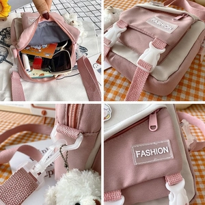 Detail view of pink and white canvas crossbody bag with compartments and fashion label