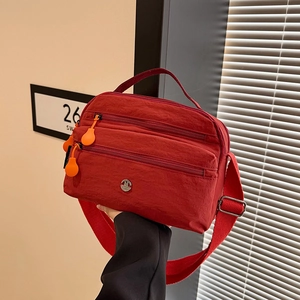 Red lightweight nylon crossbody bag for women with three zipper compartments and wide strap