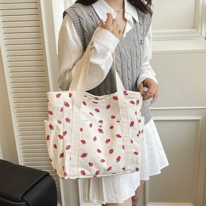 Dettaglio della borsa tote in velluto bianco con stampa di fragole e manici in tela