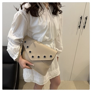 Détail de la pochette enveloppe en cuir beige avec de grands œillets métalliques