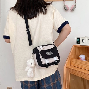 Close-up of casual canvas crossbody bag with cute plush bear charm and fashion label