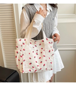Dettaglio della borsa tote in velluto a coste bianco con stampe di fragole e tracolle rinforzate