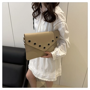 Détail de la pochette enveloppe en cuir beige avec œillets rivetés et anneaux en métal