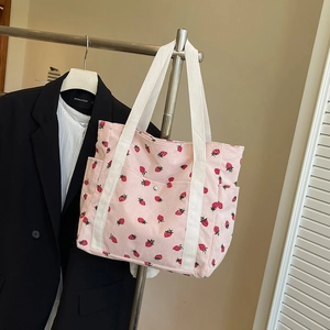 Dettaglio della borsa tote in velluto a coste rosa con stampe di fragole e manici bianchi
