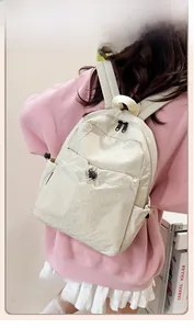Side view of a cream white nylon travel backpack with front pocket and adjustable straps
