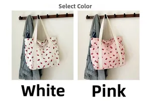 Dettaglio delle borse tote in velluto a coste bianco e rosa con motivi di fragole e clip