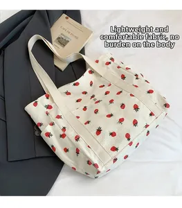 Dettaglio della borsa tote in velluto con stampa di fragole e tasca con bottone