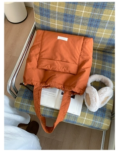 Detail of quilted orange tote bag made of waterproof nylon fabric on checkered chair