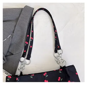 Detail of cherry print shoulder bag with black fabric strap and silver metal chain link