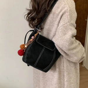 Borsa a secchiello retrò in camoscio nero con cuciture a contrasto e pompon colorati