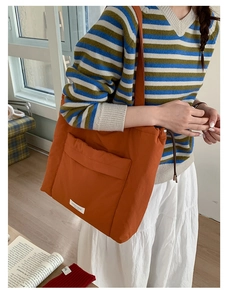 Close-up of orange drawstring tote bag with functional front pocket and nylon texture