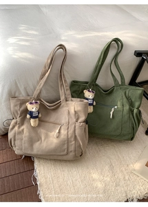 Detail minimalistischer Cord-Einkaufstaschen in Beige und Grün mit Plüschbären-Anhänger