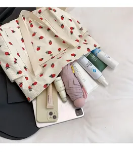 Dettaglio della capiente borsa tote in velluto a coste con stampa di fragole e tablet