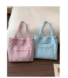 Detail of pink and blue quilted drawstring tote bags on white bedding in home setting