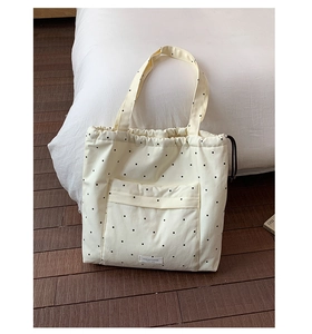 Detail of off-white canvas tote bag with black polka dots and drawstring closure