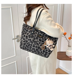 Detail of plush leopard print tote bag with black leather straps and brand plate