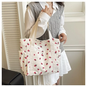 Dettaglio della borsa tote in velluto a coste beige con stampa di fragole e fibbia in metallo