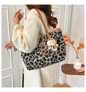 Detail of leopard print plush tote bag with brown leather strap and cute charm