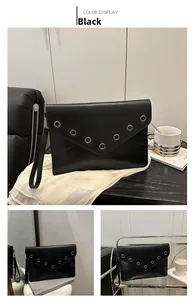 Détails d'une pochette enveloppe noire avec rivets métalliques et dragonne de poignet