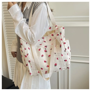 Dettaglio della borsa tote in velluto a coste bianco con motivi a fragola e ampi spallacci