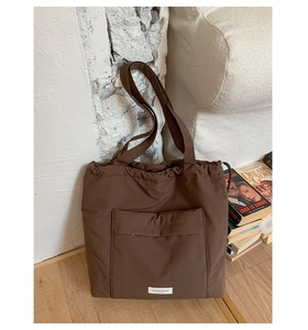 Detail of coffee brown nylon tote bag featuring front pocket and drawstring closure