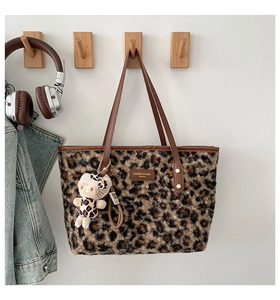 Close-up of leopard print plush tote bag featuring a brand plaque and cute kitty charm